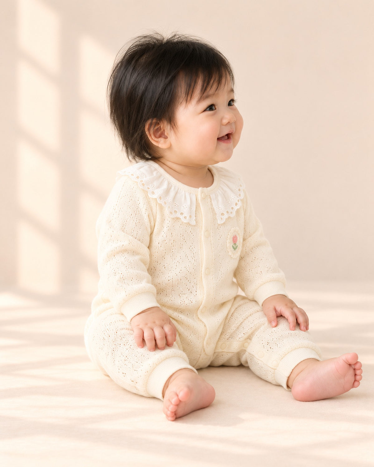 Side view of the knit romper showing the ribbed cuffs – Cream