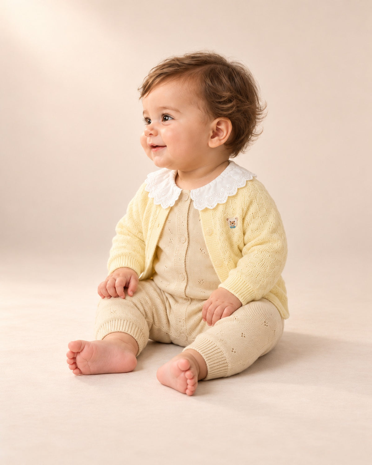 Side view of the jumpsuit and lace collar on a seated baby – Oatmeal