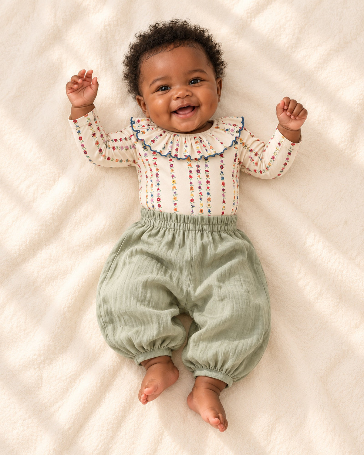 Front view of a baby in sage balloon pants and a ruffle collar bodysuit, full length – Sage