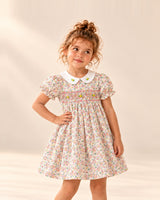 Girl in the Rosie smocked floral dress with a white Peter Pan collar, hand on hip – Pink Floral