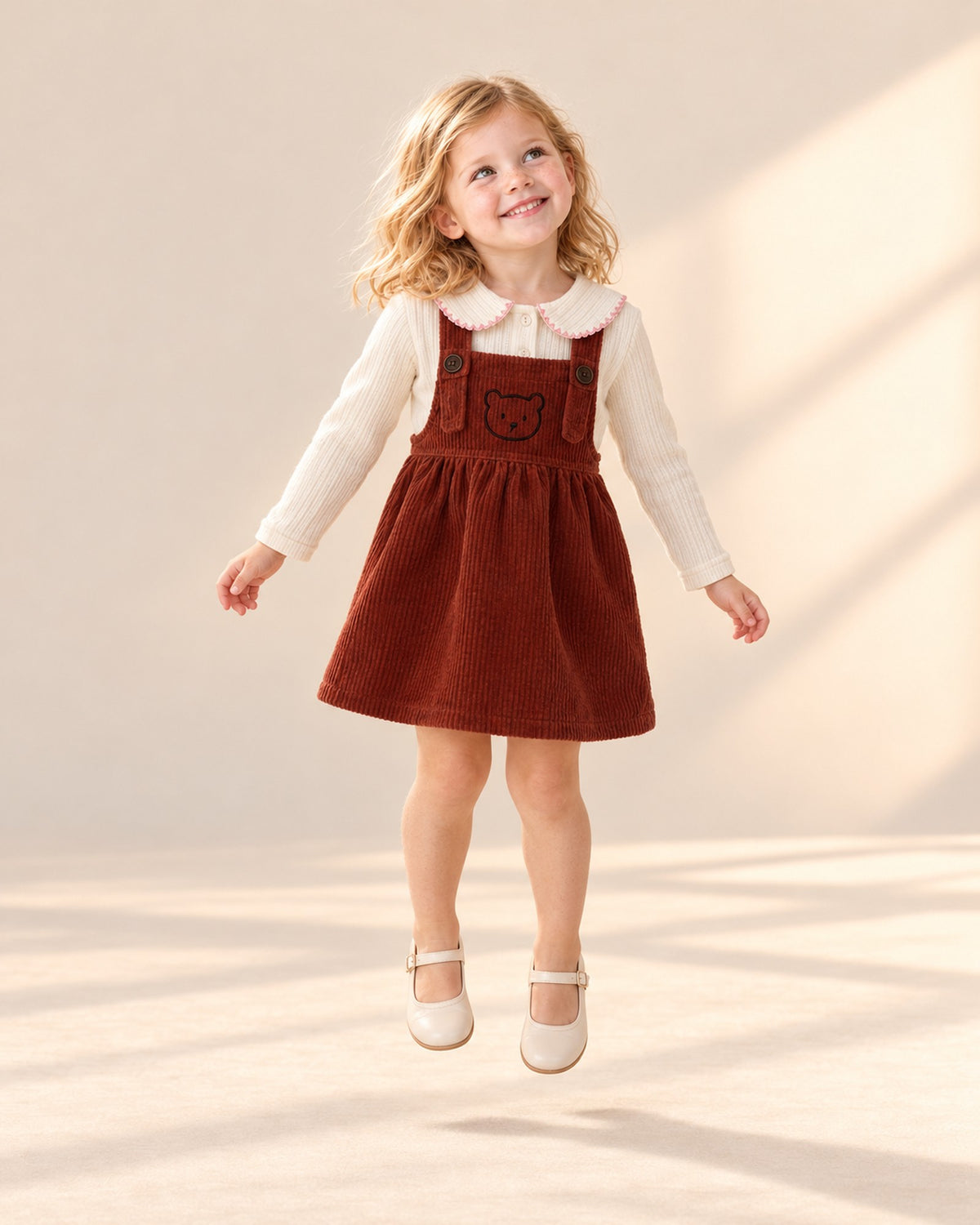 Girl in the rust teddy pinafore and cream rib top with the pink-edged collar, head to toe – Cream