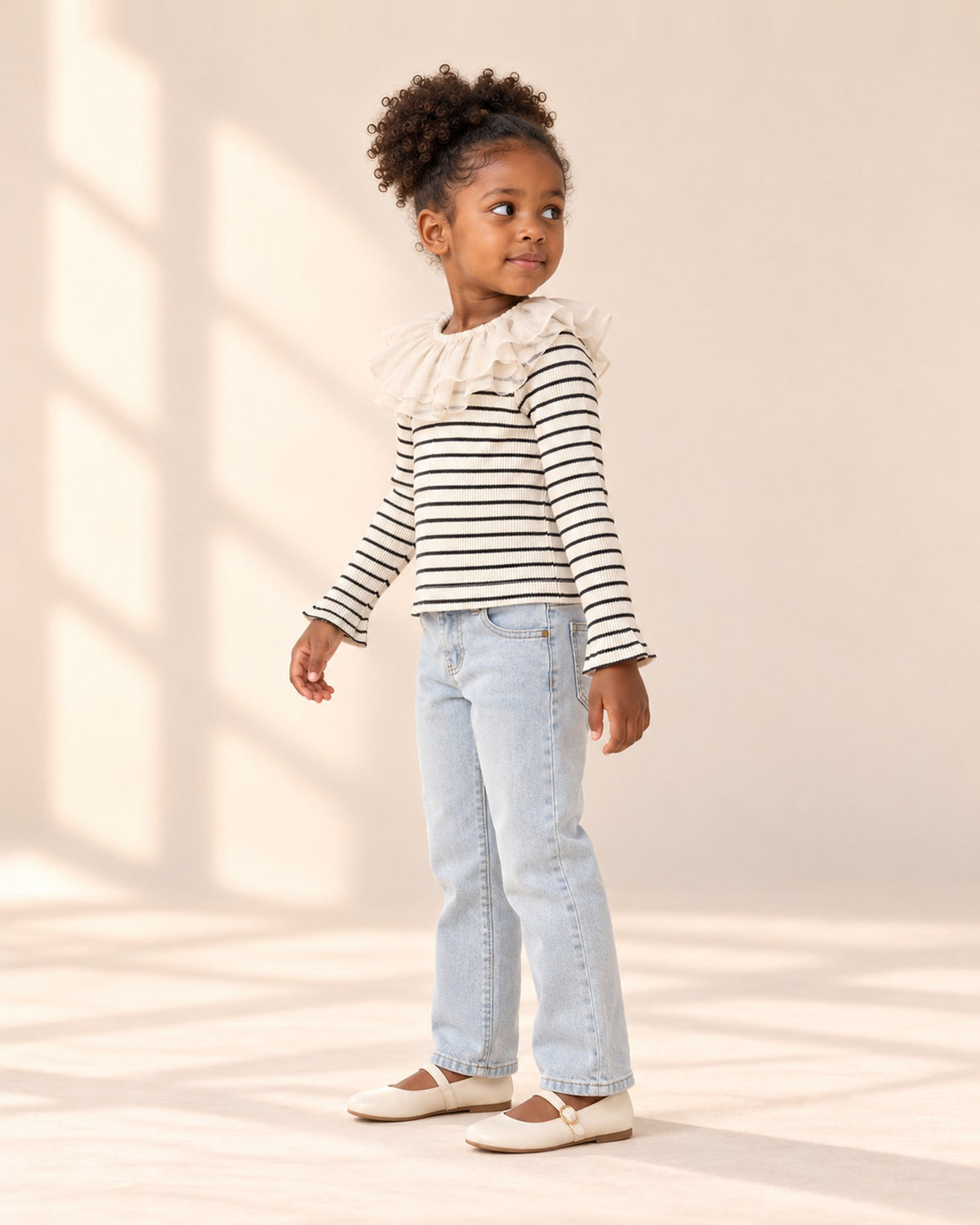Side view of the striped ruffle collar top showing the striped sleeve and sheer ruffle collar, worn with light-wash straight jeans – Black Stripe