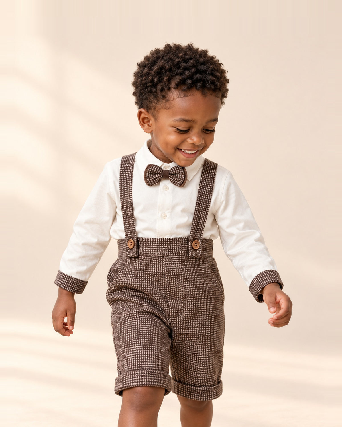 Boy walking in the Teddy houndstooth shortalls, white shirt and bow tie – Brown Check