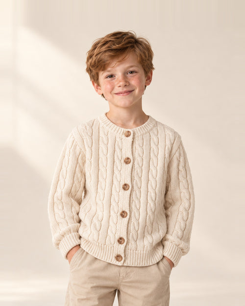 Boy with hands in pockets wearing the Arthur cream cable knit cardigan – Cream