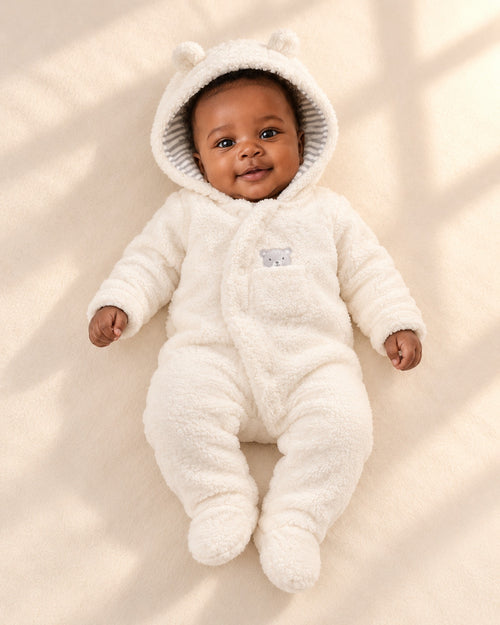 Baby lying down in the Barney cream sherpa pram suit with bear ears – Cream