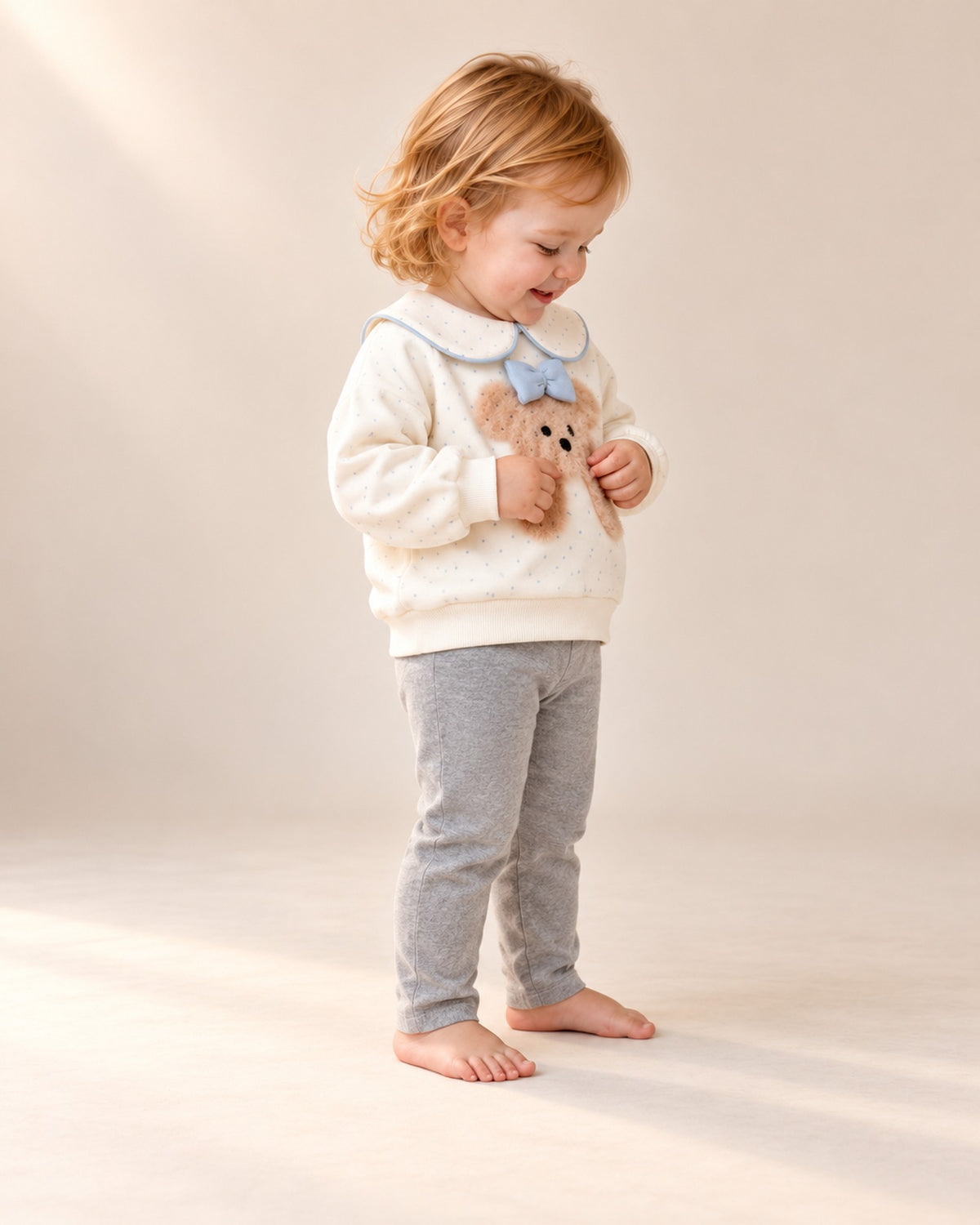 Side view of the toddler in the teddy bow collar sweatshirt – Cream