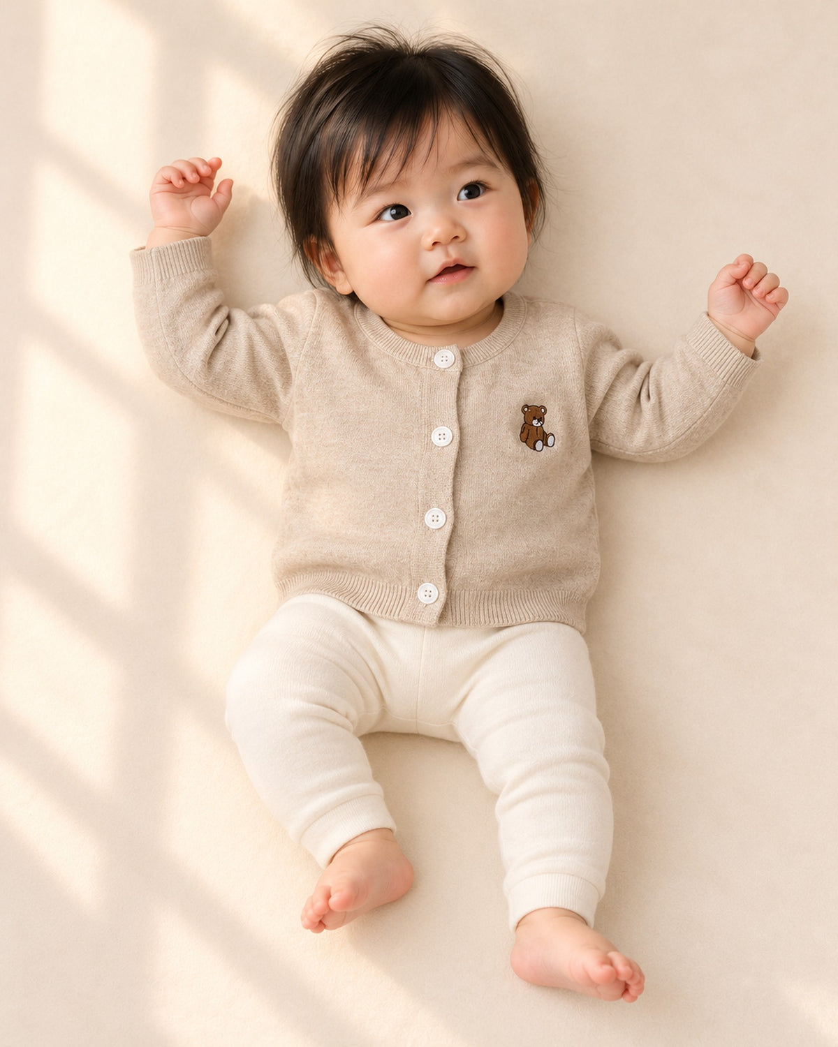Front view of a baby in the open oatmeal cardigan over a lace collar knit romper, full length – Oatmeal
