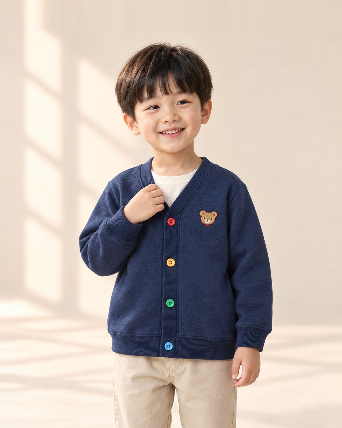 Boy smiling in the Toby navy cardigan with rainbow buttons – Navy