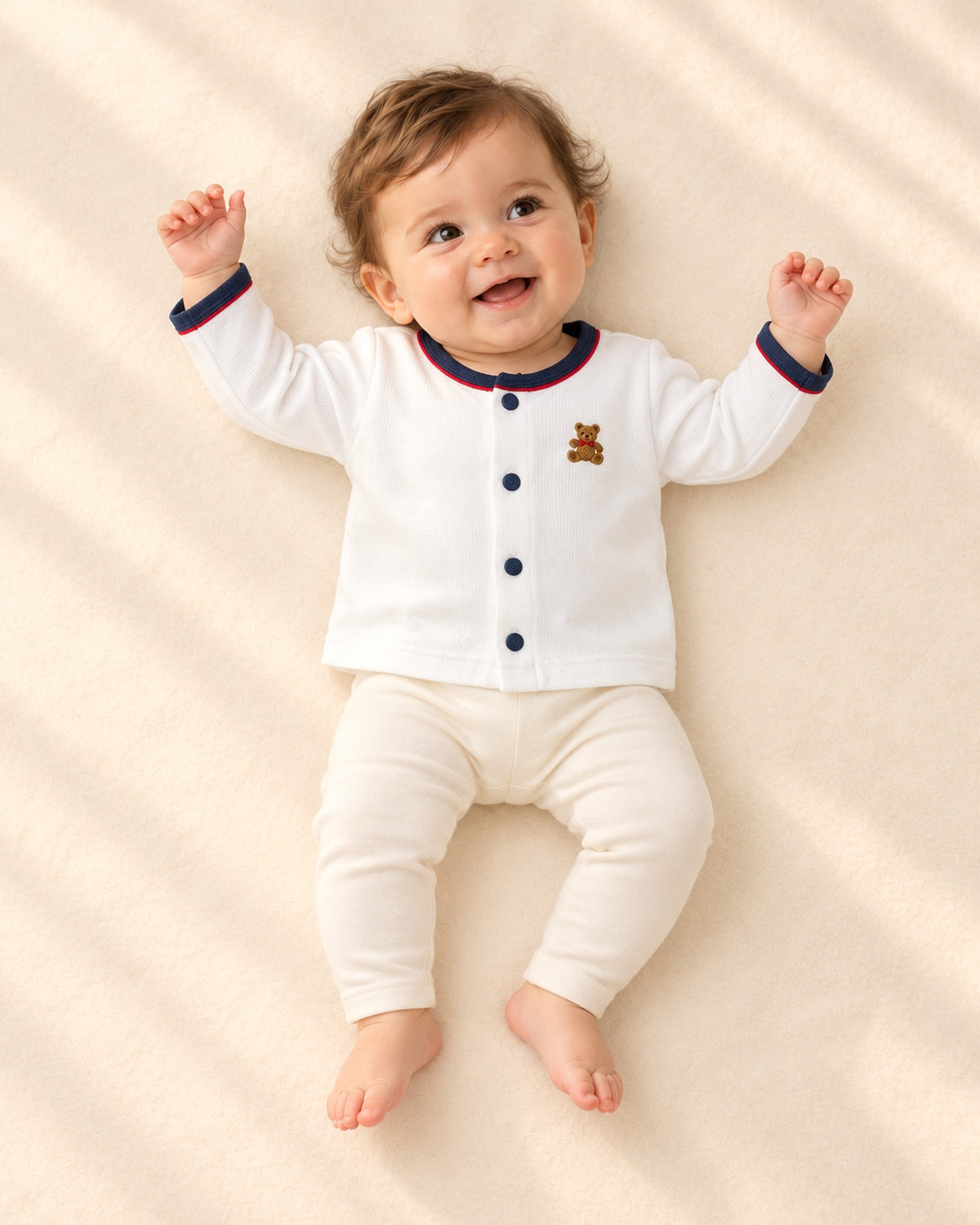 Front view of a baby in the open white cardigan over a dusty blue bubble romper, full length – White