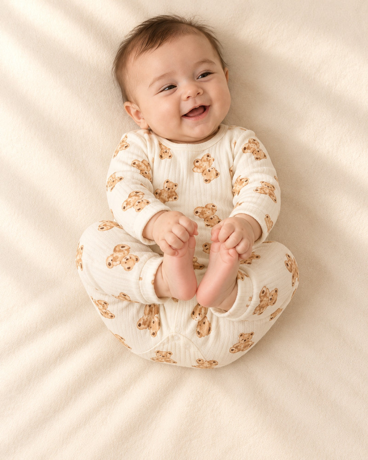 Baby lying relaxed in the cream bear romper with the brown bear lovey nearby – Cream