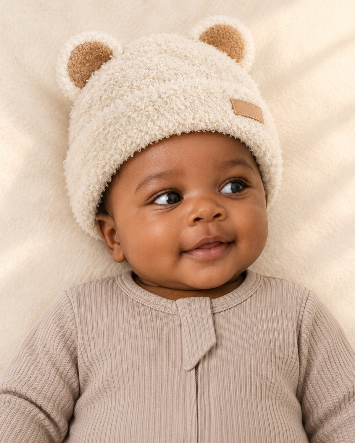 Head-and-shoulders view of a baby in the cream teddy beanie with bear ears – Cream