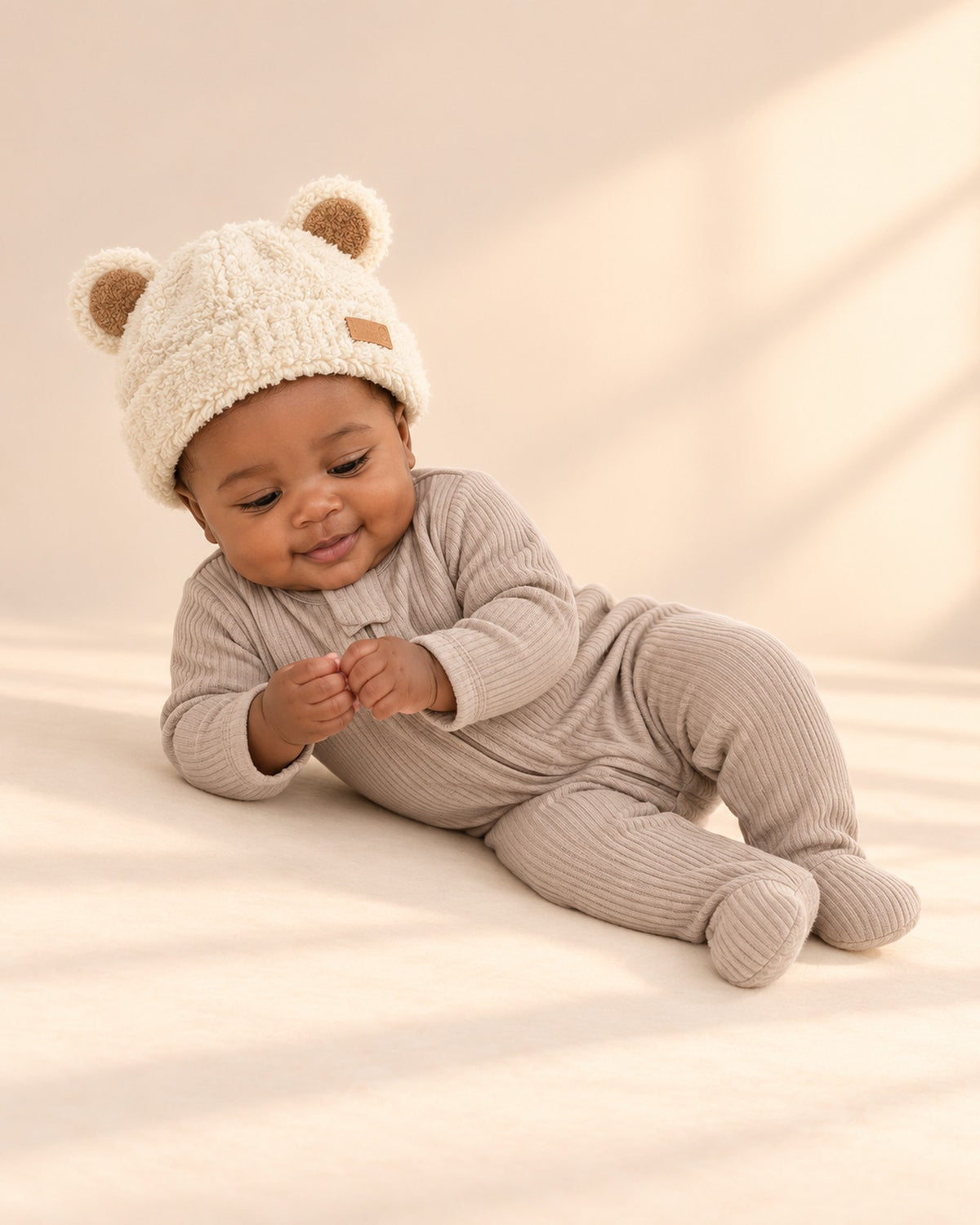 Baby smiling in the fluffy cream beanie and ribbed footie – Cream