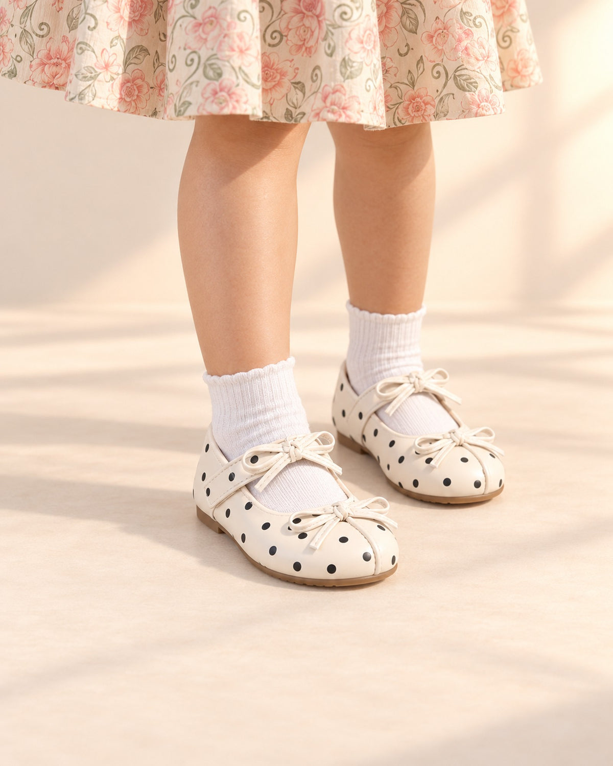 Close-up of cream Mary Janes with black polka dots and thin cord bows – Cream Dot