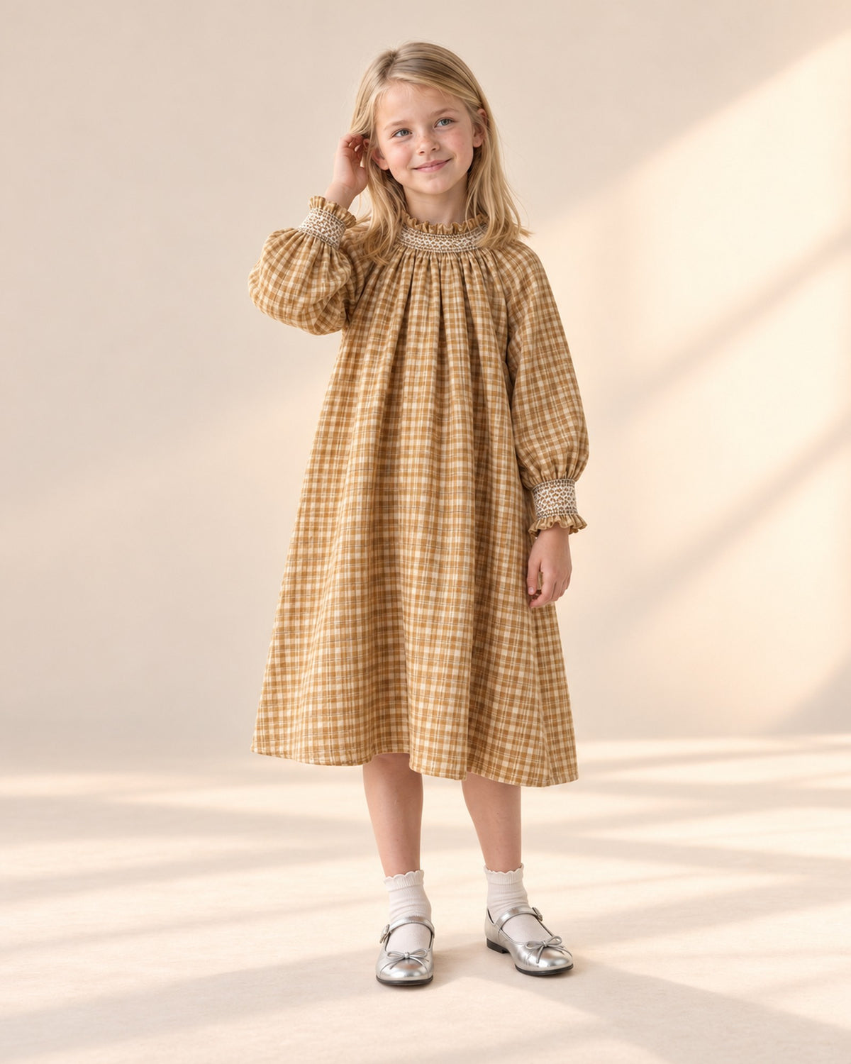 Front view of a girl in an ochre check smock dress, white ankle socks and silver bow flats, full length – Silver
