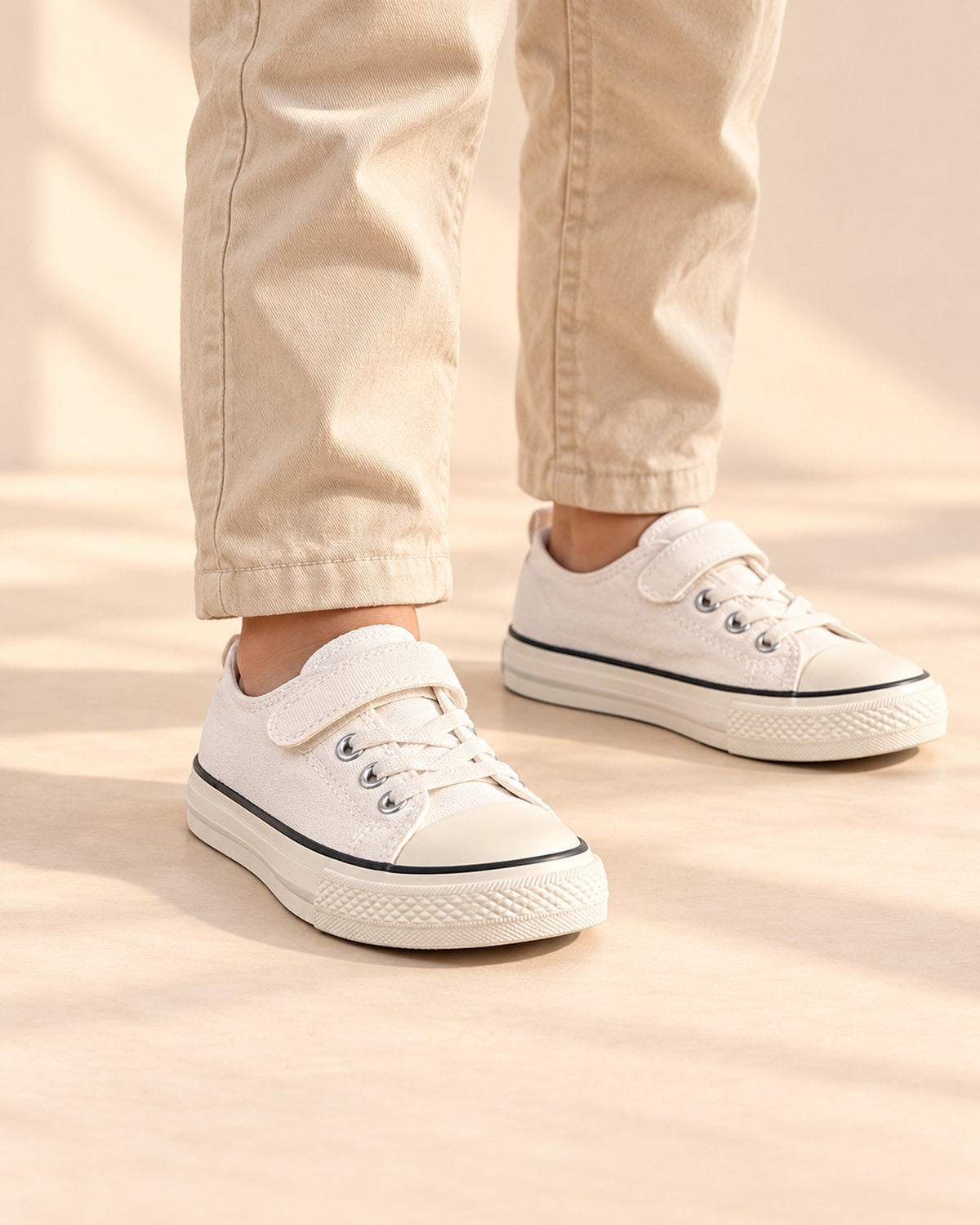 Close-up of white low canvas sneakers with a hook-and-loop strap and rubber toe cap – White