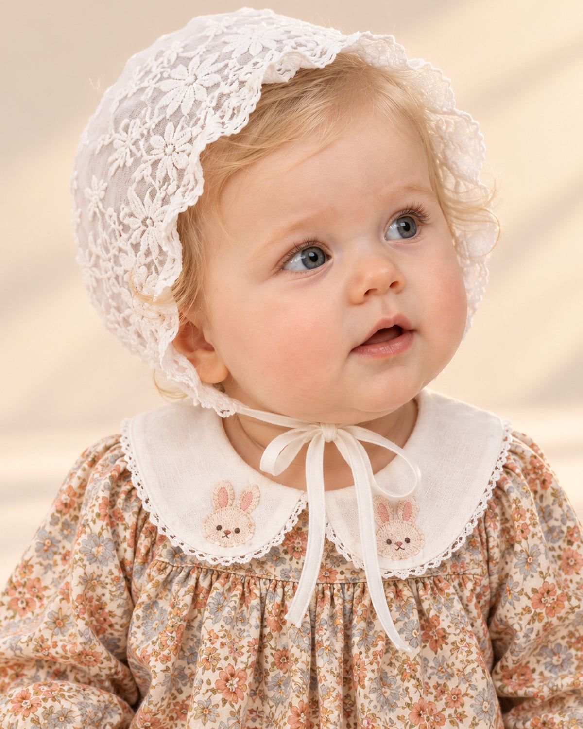White floral lace baby bonnet with a ruffled brim and ribbon ties
