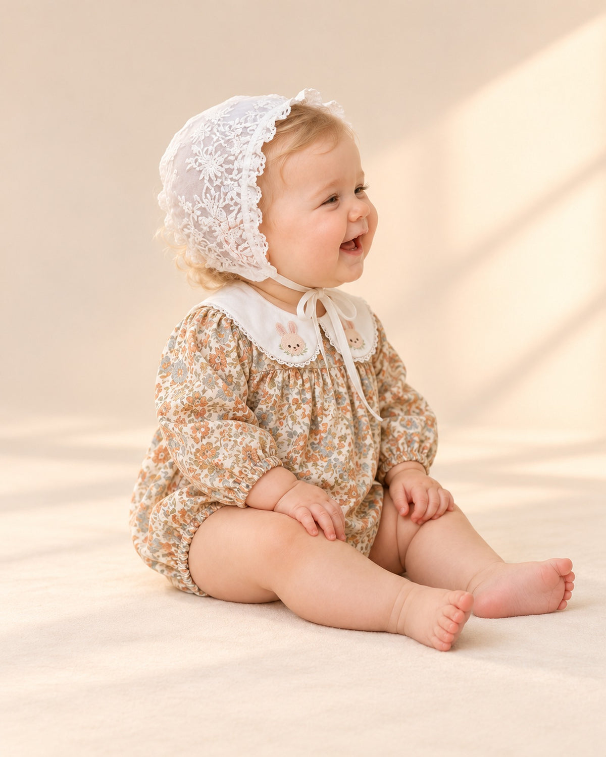 Side view of the white lace bonnet and its ribbon tie with the bubble romper – White