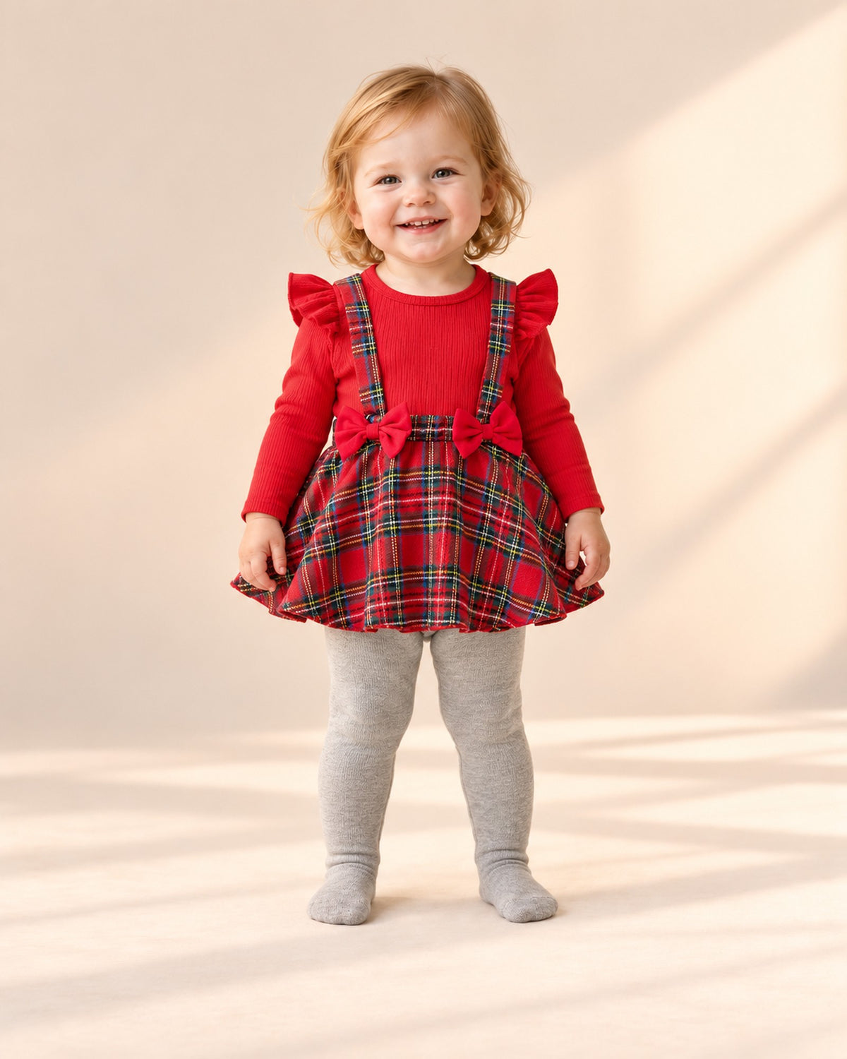 Front view of a toddler in a red tartan outfit and grey ruffle tights, full length – Grey