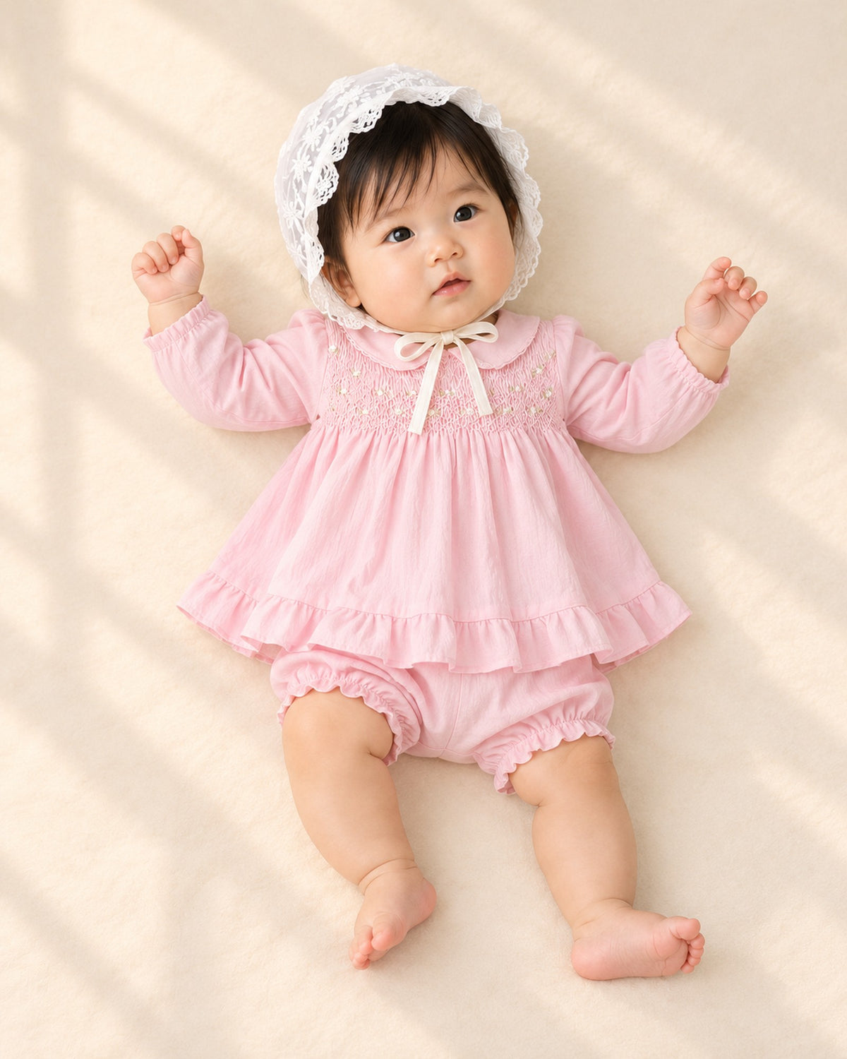 Front view of a baby in the pink smocked set and a white lace bonnet, full length – Pink
