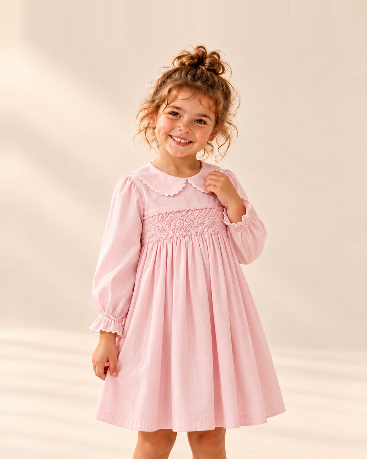 Girl smiling in the Penny pink smocked dress with a scalloped collar – Pink