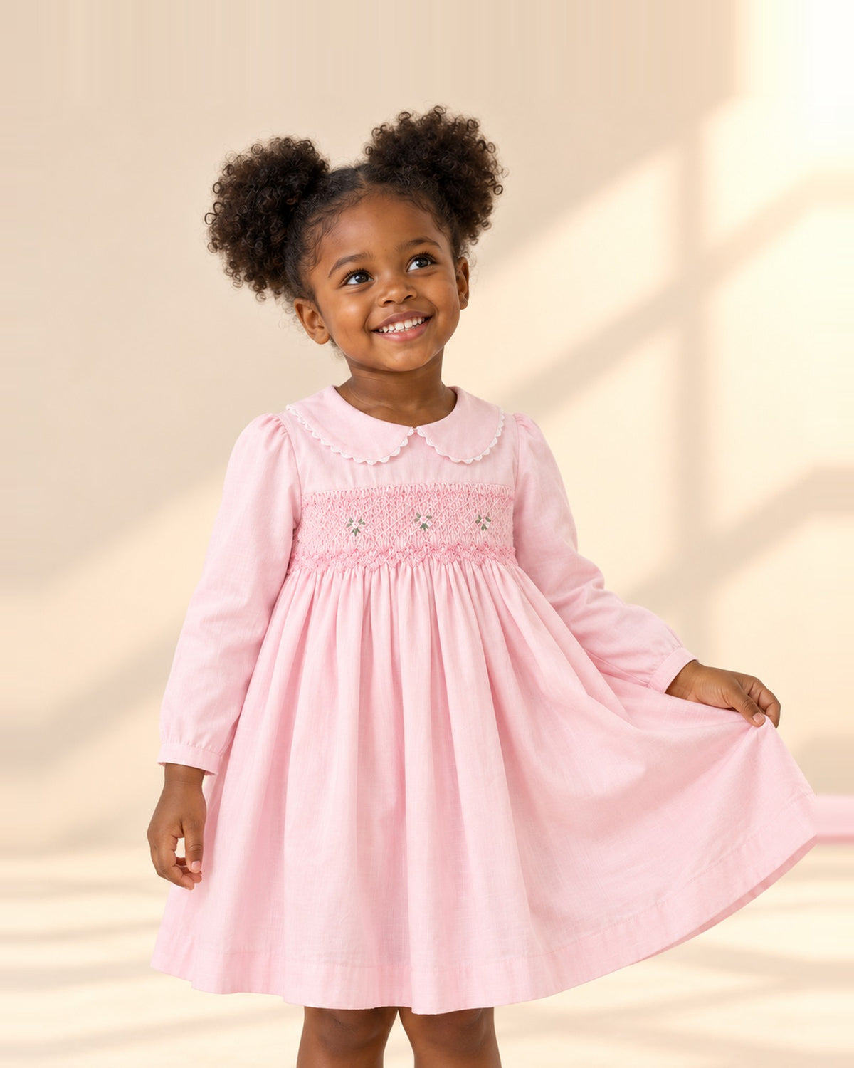 Girl smiling in the Evelyn pink smocked dress with embroidered flowers – Light Pink