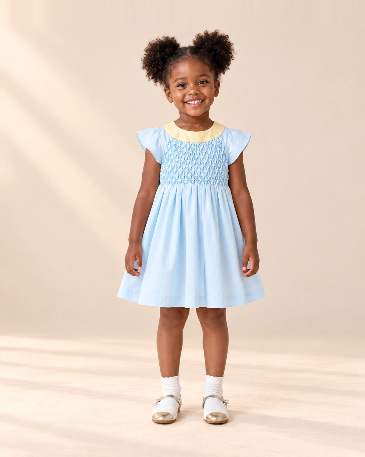 Front view of a girl in the blue smocked dress, white ankle socks and pearl strap Mary Janes, full length – Light Blue