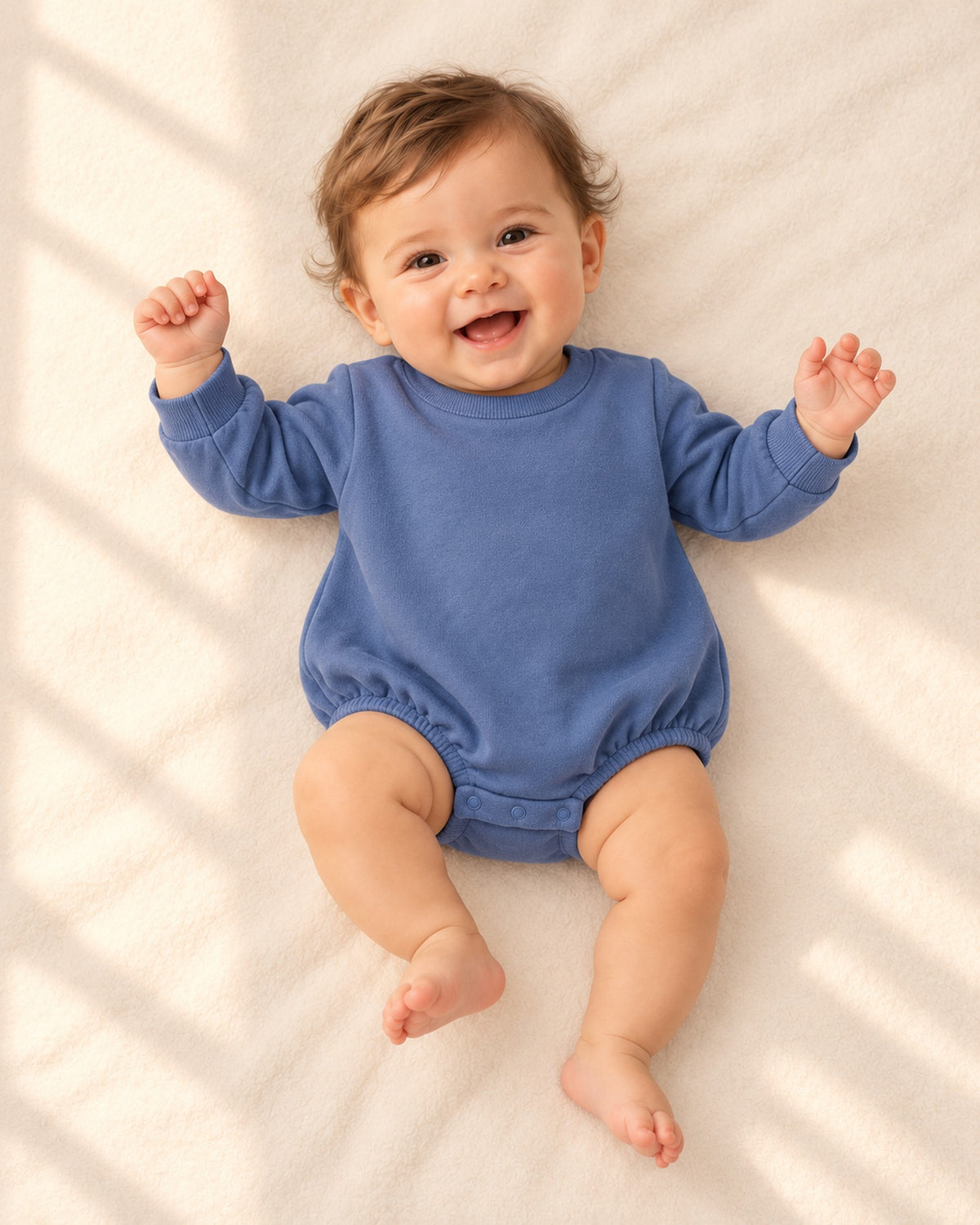 Front view of the blue bubble romper on a smiling baby lying down – Dusty Blue