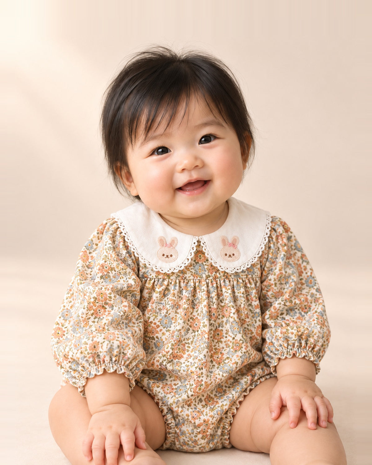 Baby smiling in the Dottie floral bubble romper with a bunny collar – Vintage Floral