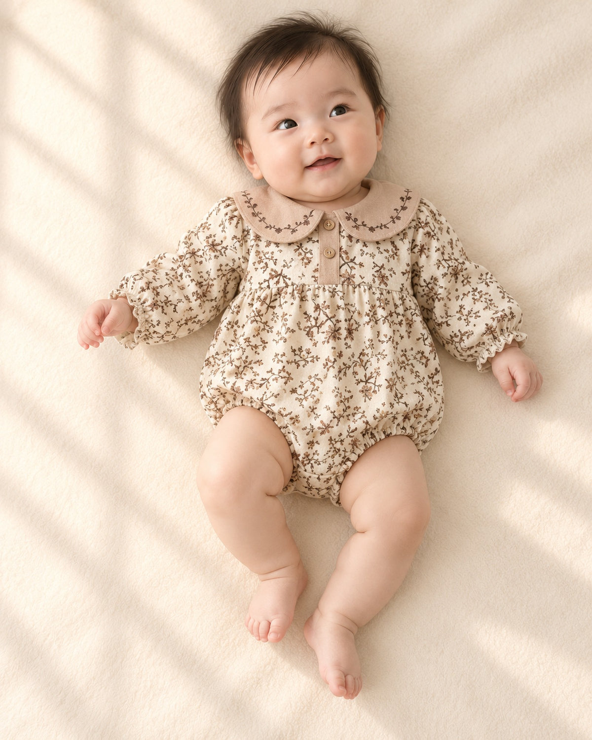 Baby lying in the Opal vintage floral bubble romper with a latte collar – Cream Floral