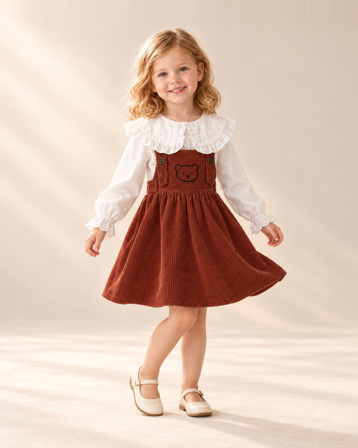 Girl at play in the rust pinafore with embroidered teddy bear, styled with the ruffle collar blouse – Rust