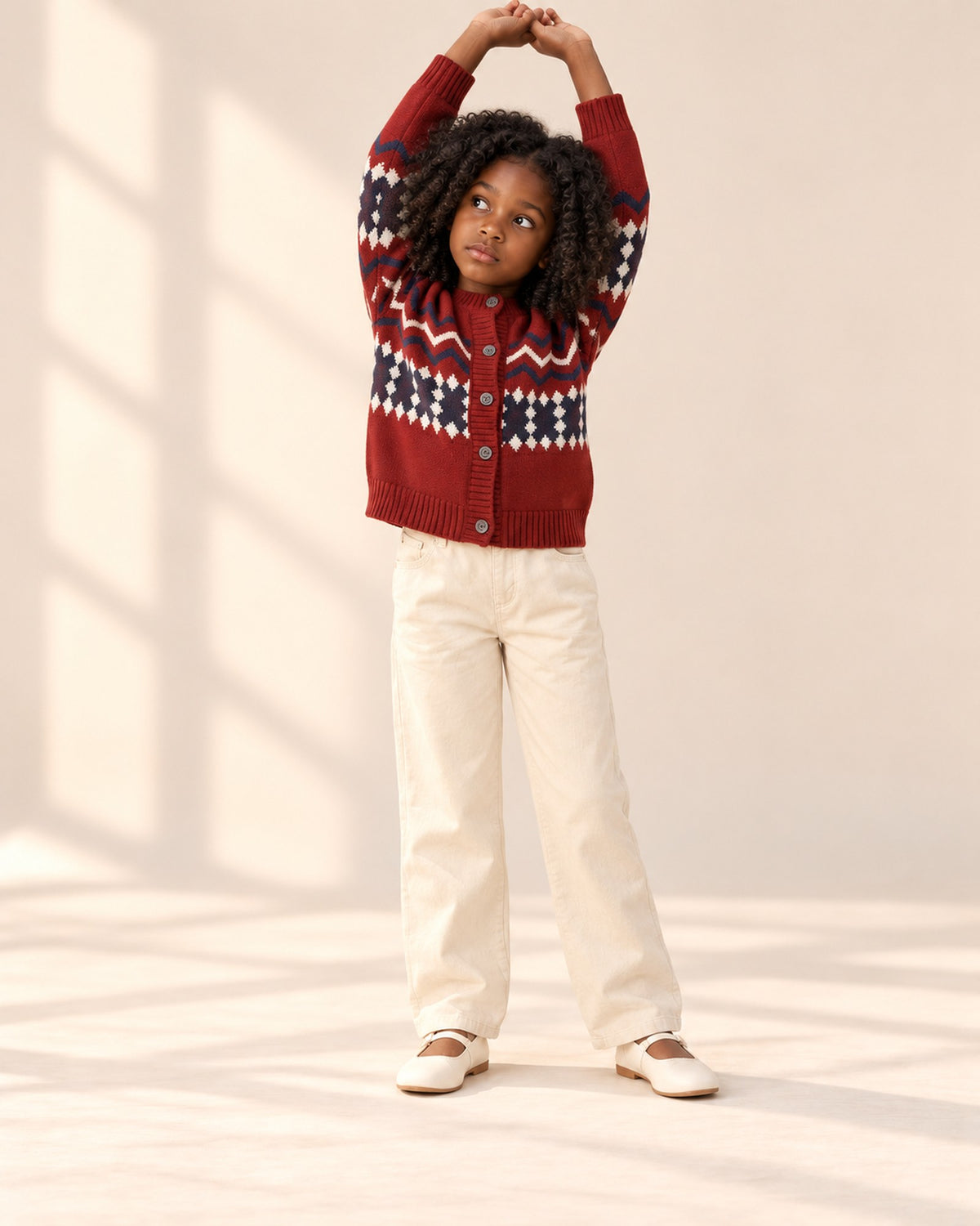 Girl stretching her arms up in the red Fair Isle cardigan – Red