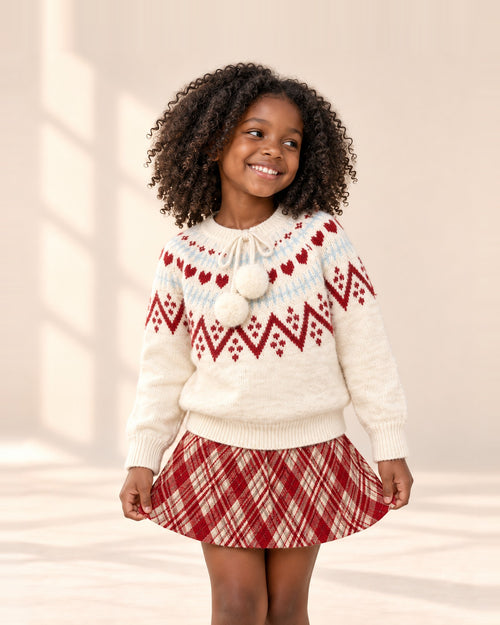 Girl in the Clementine heart sweater and plaid skirt, holding the skirt out – Cream & Red