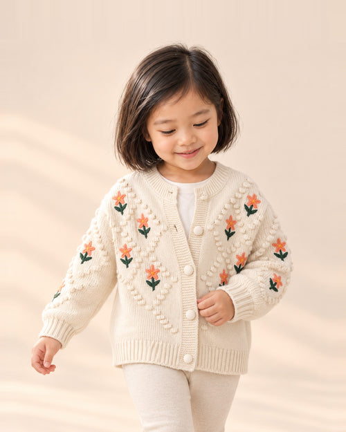 Girl in the Flora cream cardigan with embroidered peach flowers – Cream