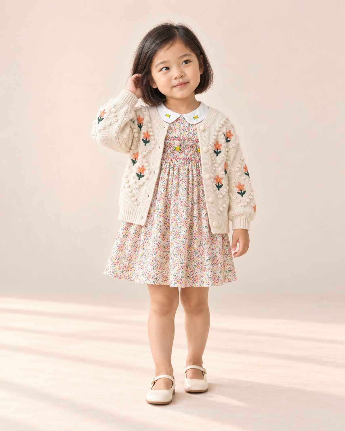 Full-length front view of the embroidered flower knit cardigan, paired with the smocked floral dress – Cream