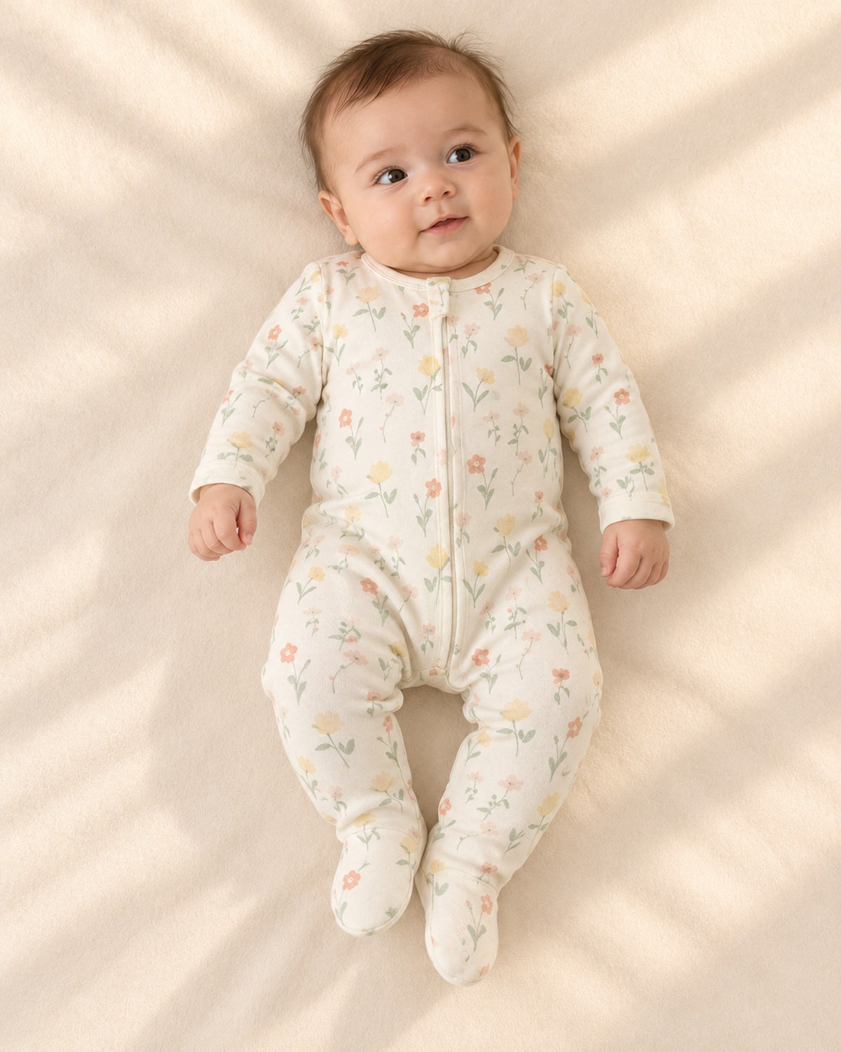 Baby lying in the Fern cream wildflower zip footie – Wildflower