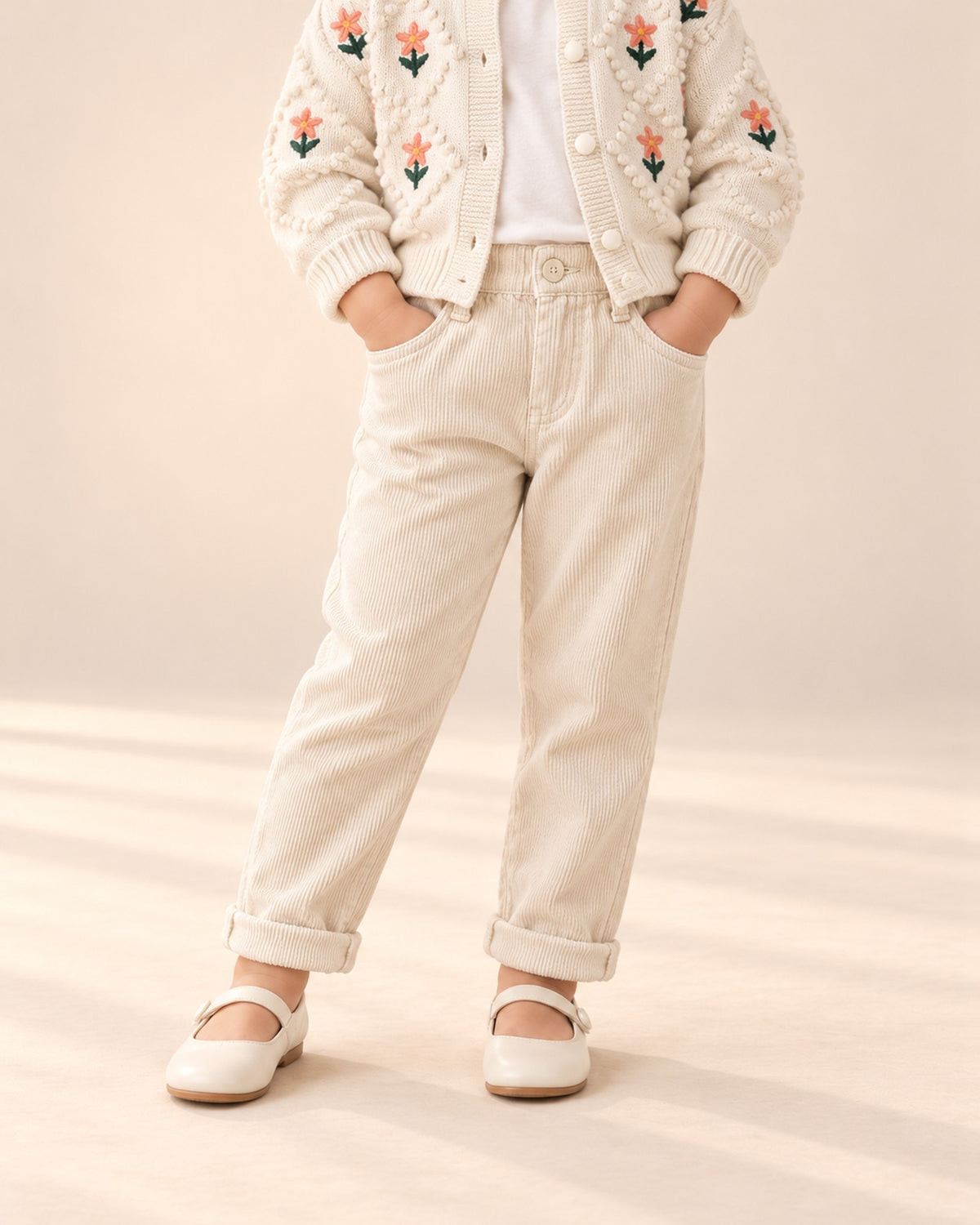 Close-up from chest to feet of cream corduroy pants with front pockets and a turned-up hem – Cream