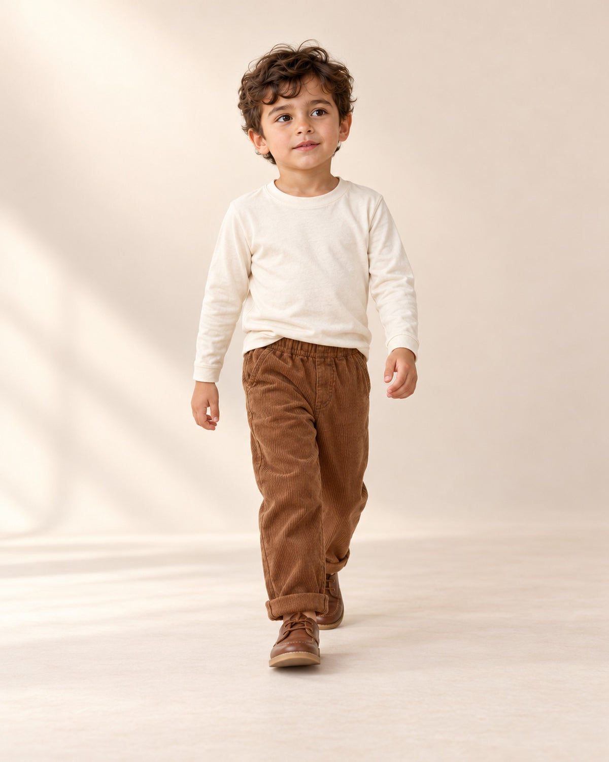 Boy sitting cross-legged in a cream long sleeve tee and corduroy pants – Cream