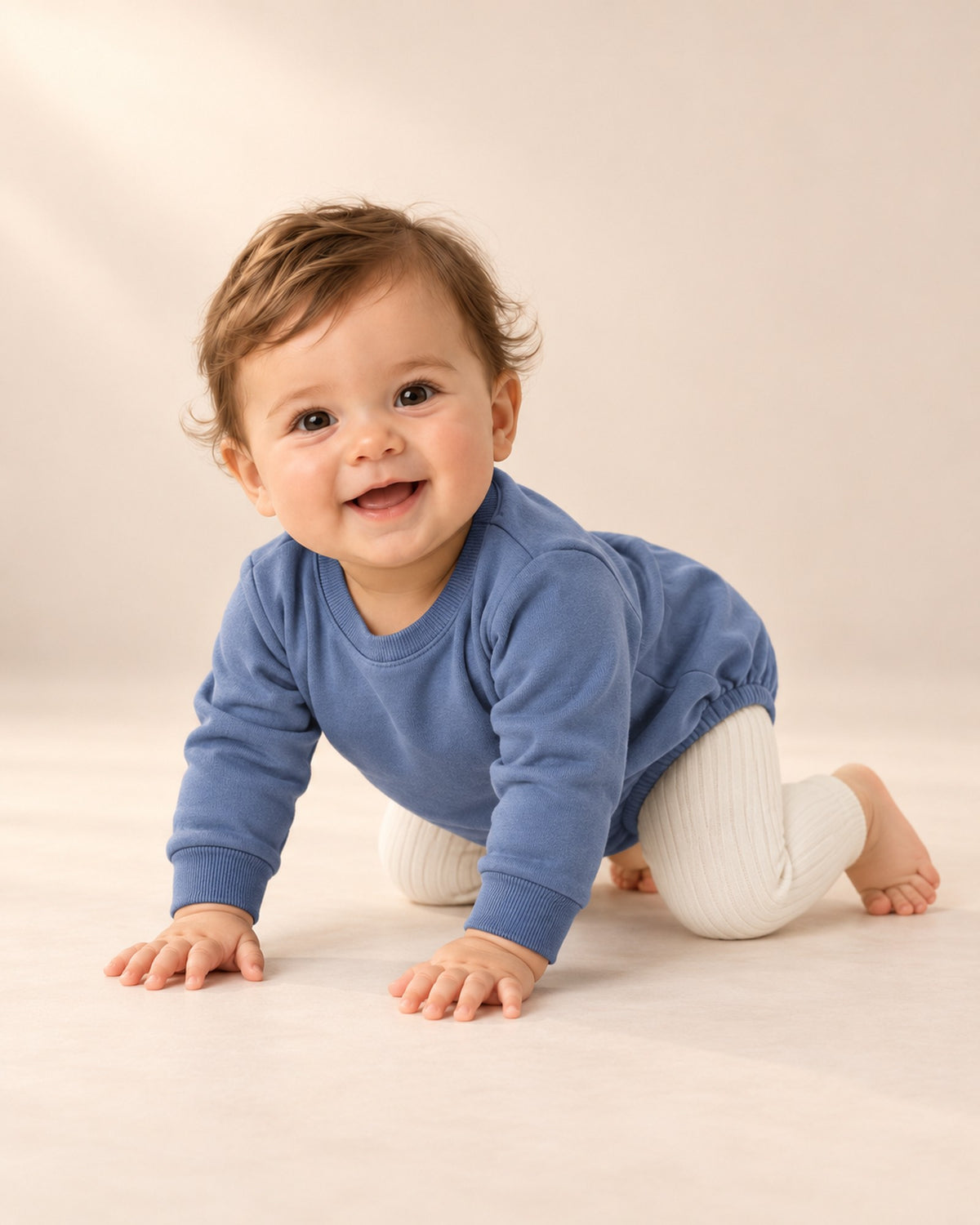 Baby sitting and playing in cream ribbed leggings and a blue bubble romper – Cream
