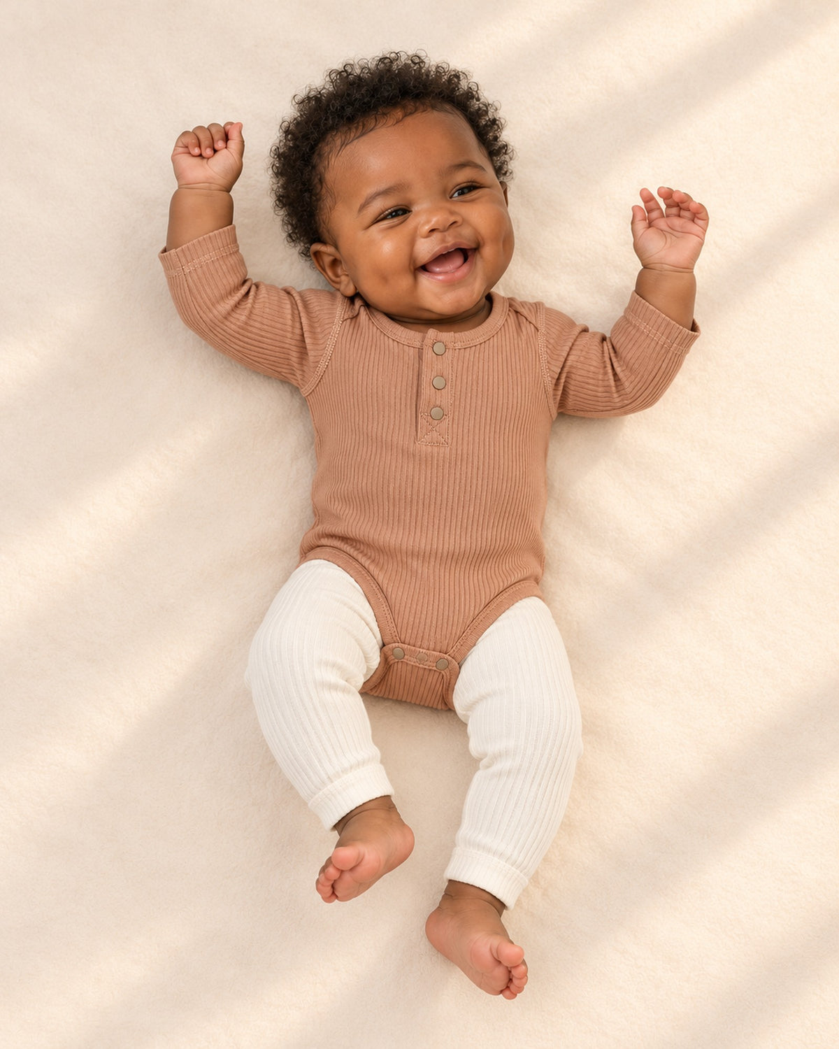 Front view of a baby in the caramel bodysuit and cream ribbed leggings, full length – Caramel