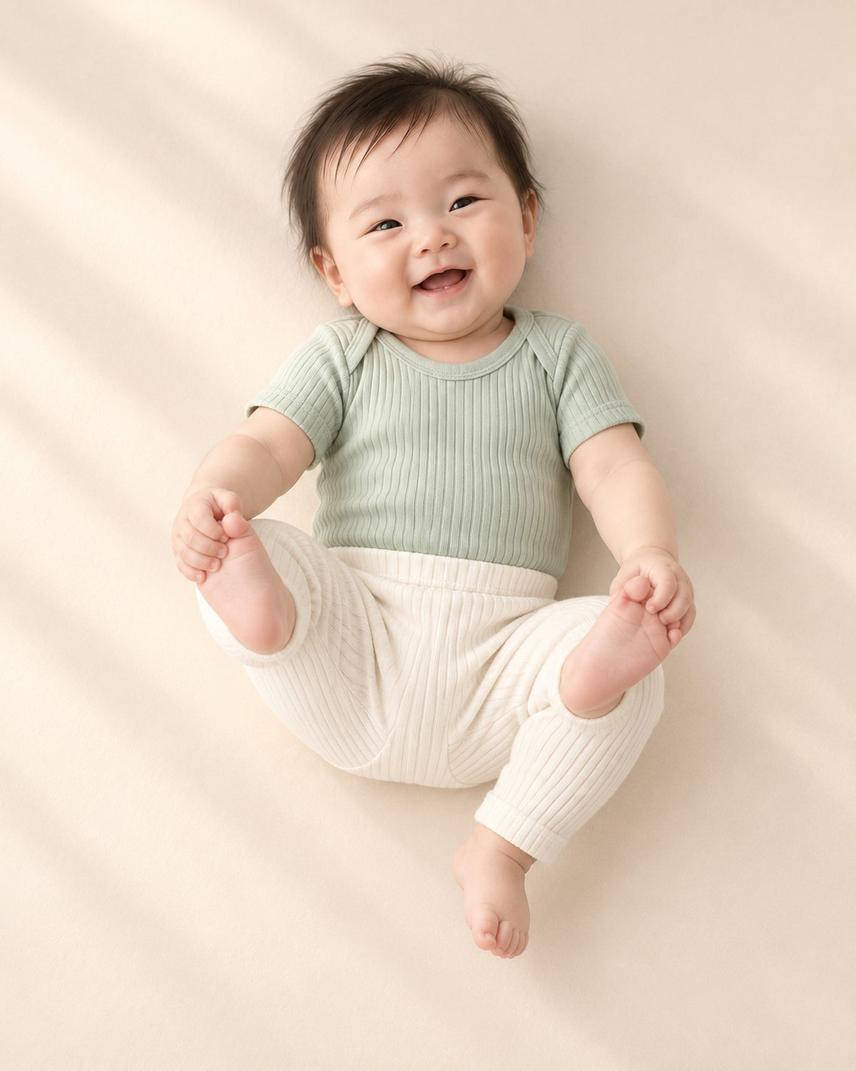 Baby in the sage ribbed bodysuit and cream leggings, shown relaxed – Sage