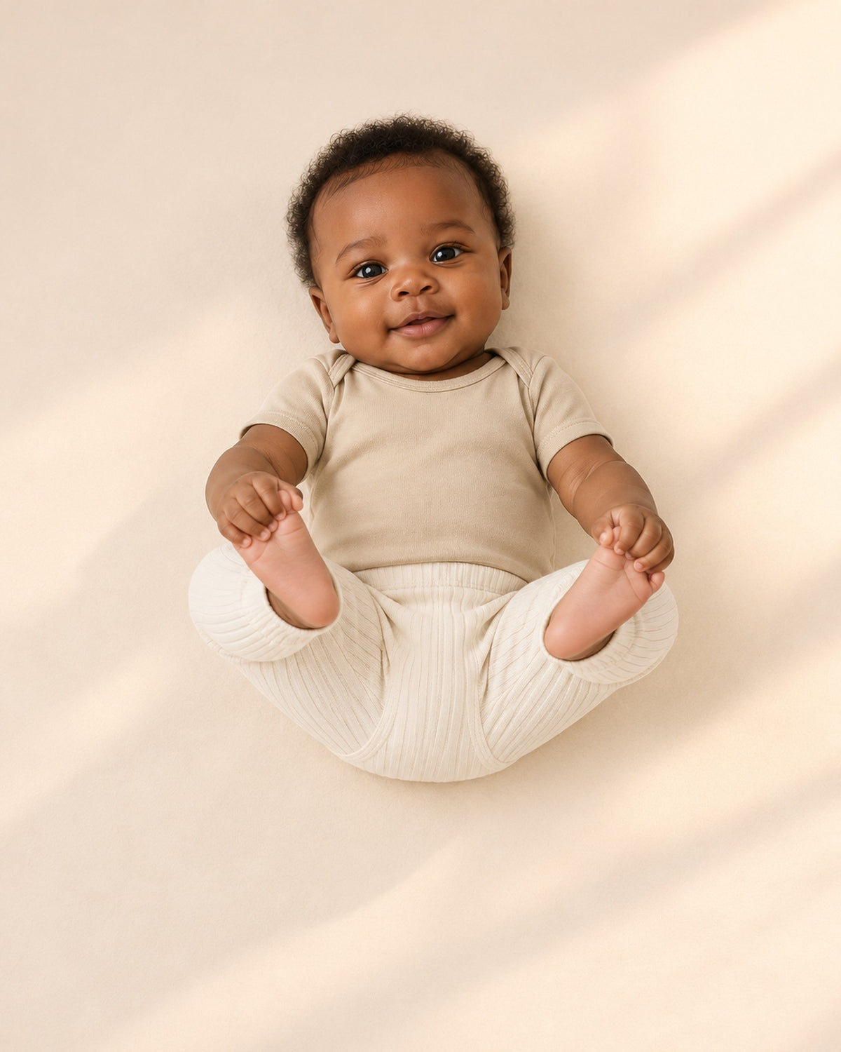 Baby in the oatmeal bodysuit and ribbed leggings, shown relaxed – Oatmeal