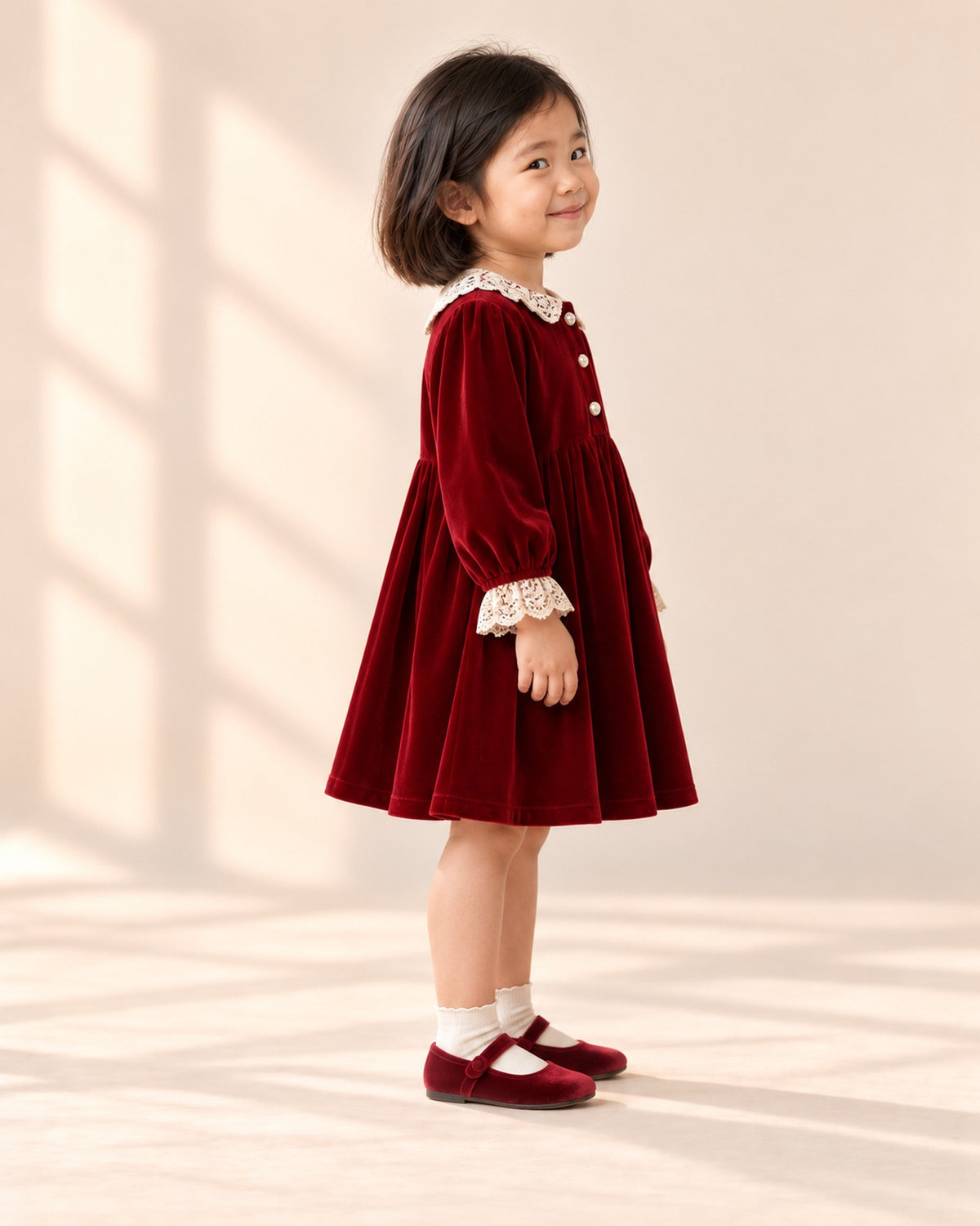 Side view of the red velvet dress showing the long sleeves and gathered skirt – Red