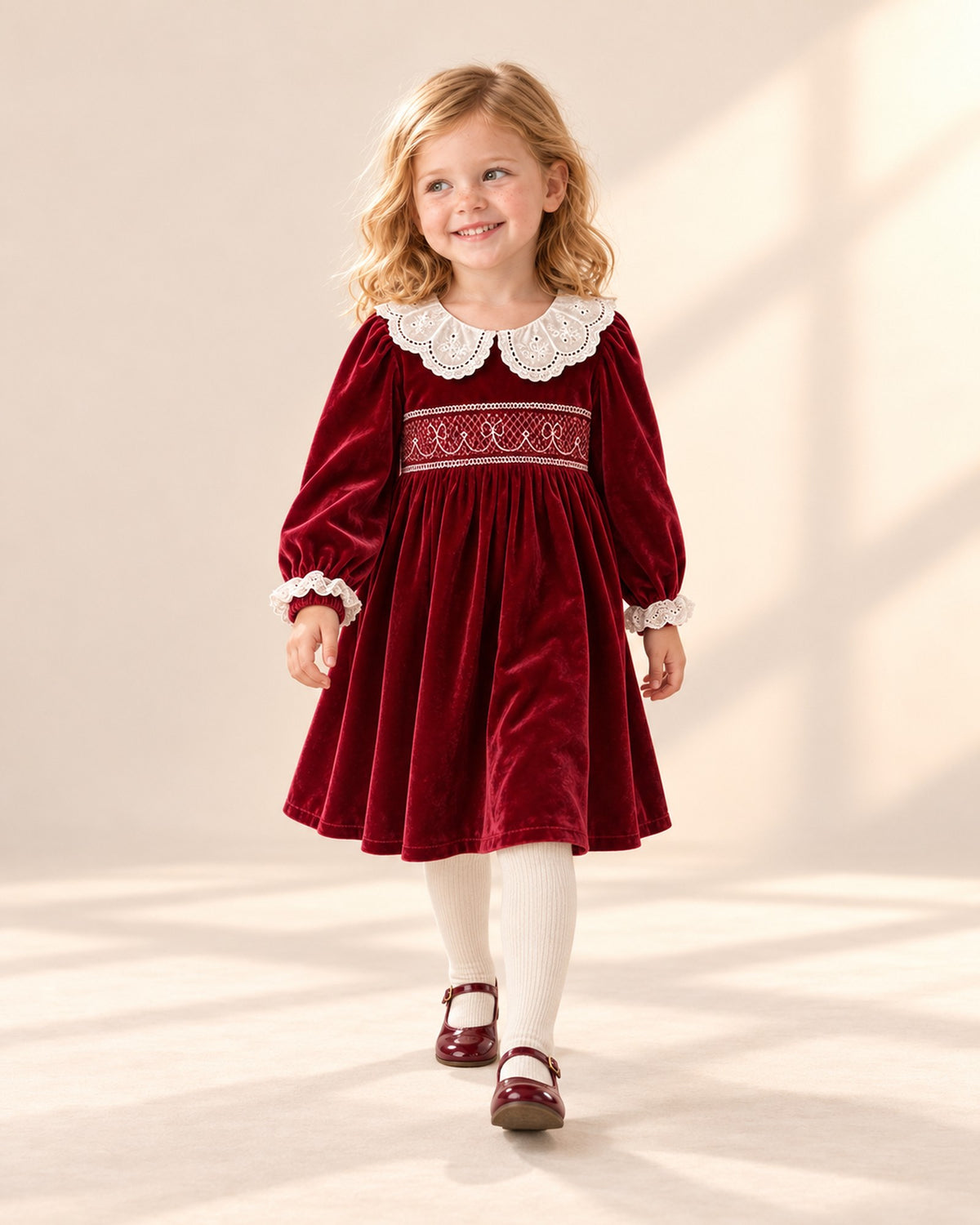 Girl in a natural pose wearing the red smocked velvet dress and cream tights – Red