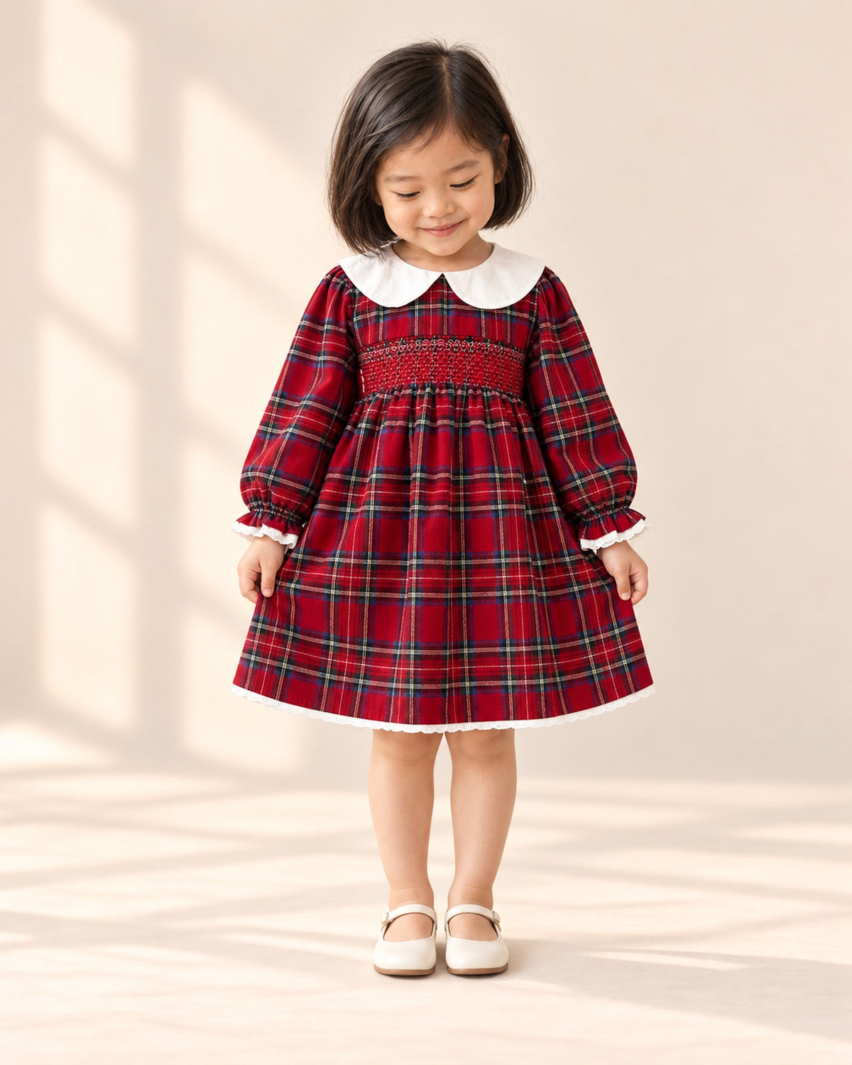 Front view of a girl in the red tartan smocked dress, white ankle socks and cream Mary Janes, full length – Red Tartan