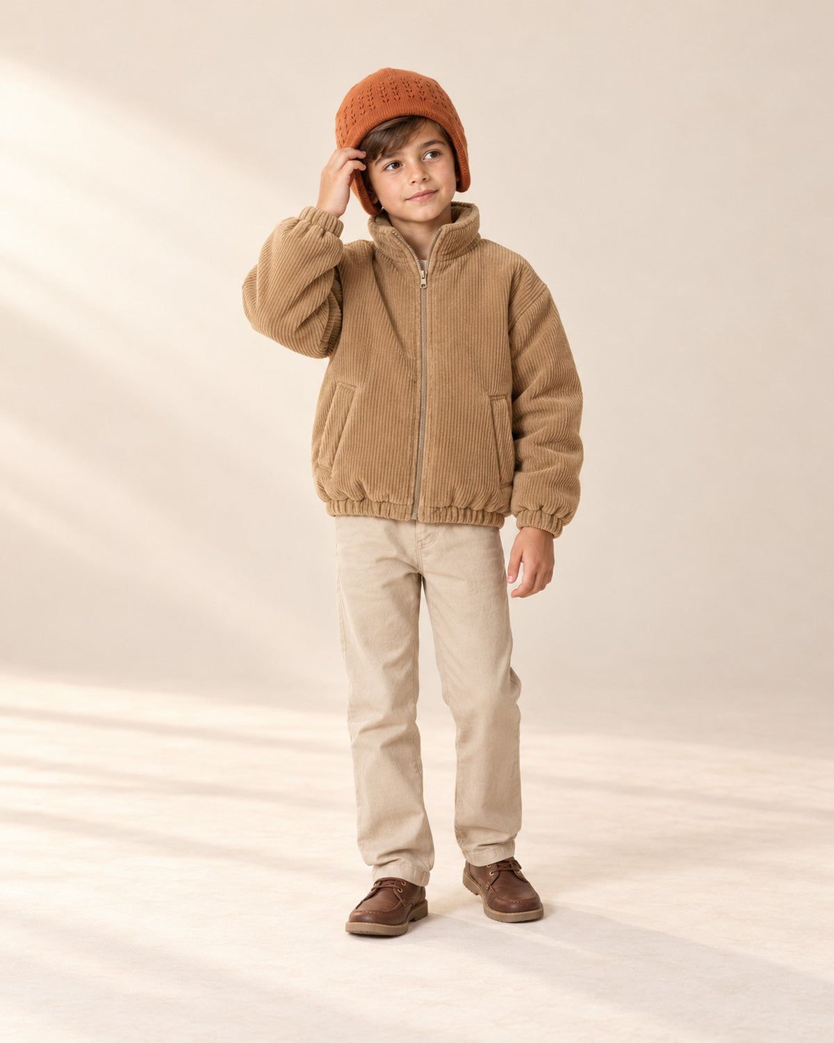 Front view of a boy in the rust earflap hat and camel corduroy jacket, full length – Rust