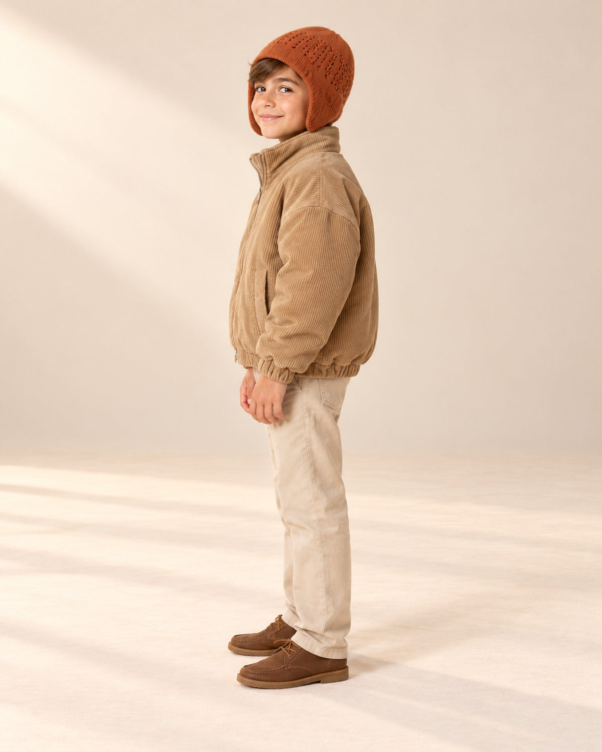 Side view of the rust knit hat with ear flap and the camel jacket – Rust