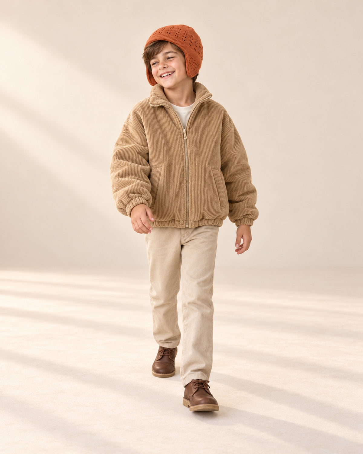 Boy in a natural pose wearing the rust knit hat and camel corduroy jacket – Rust