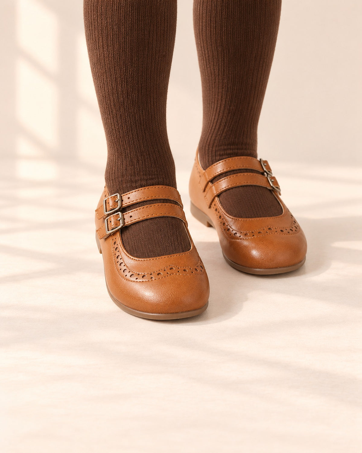 Close-up of a girl's feet in cognac double strap Mary Janes, worn with brown ribbed tights – Cognac