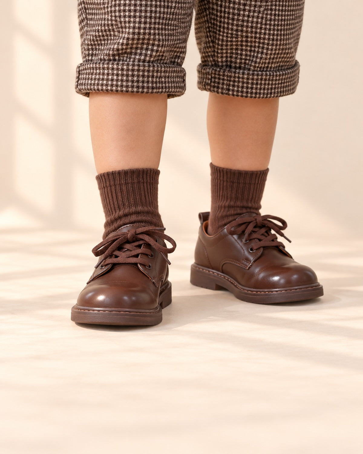 Close-up of a boy's feet in brown lace-up derby shoes with earthy crew socks – Brown