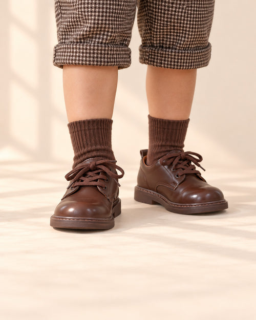Close-up of a boy's feet in brown lace-up derby shoes with earthy crew socks – Brown